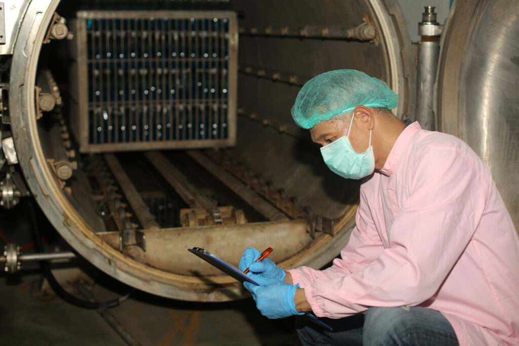 Worker controlling the work of machine in production line at beverage industry.
