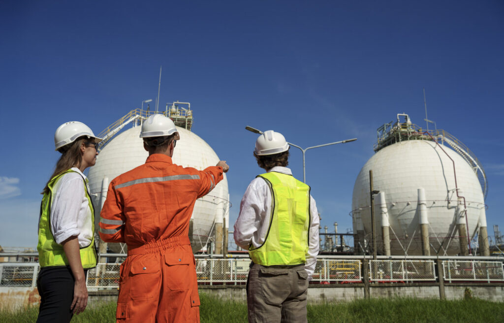 Workers discuss operational details at an industrial facility under blue skies